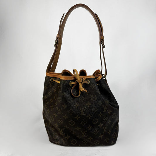 Louis Vuitton monogram canvas bucket bag with brown leather trim and a single shoulder strap, photographed against a light gray studio background.