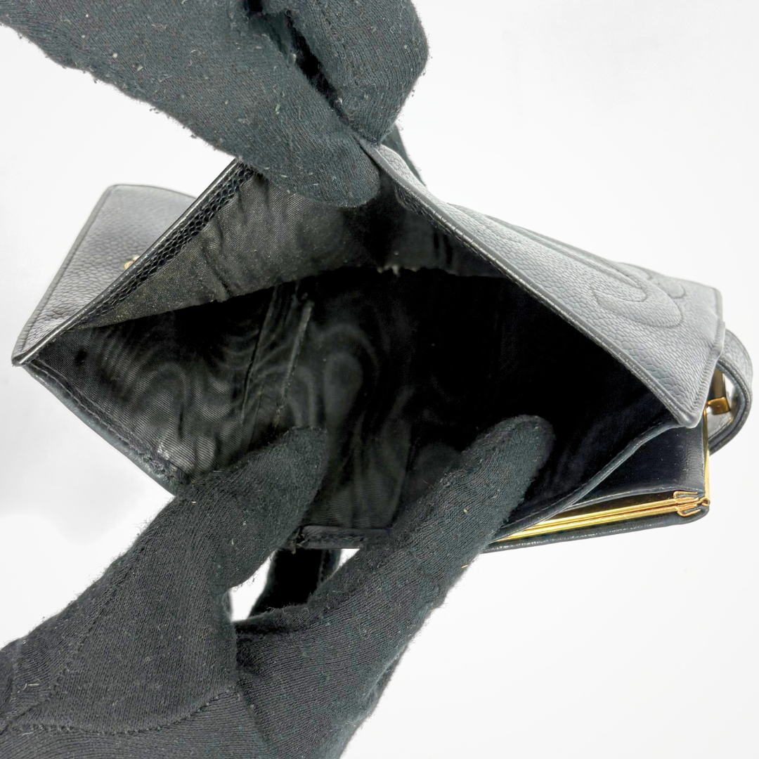 Black leather wallet held open by a gloved hand on a white background
