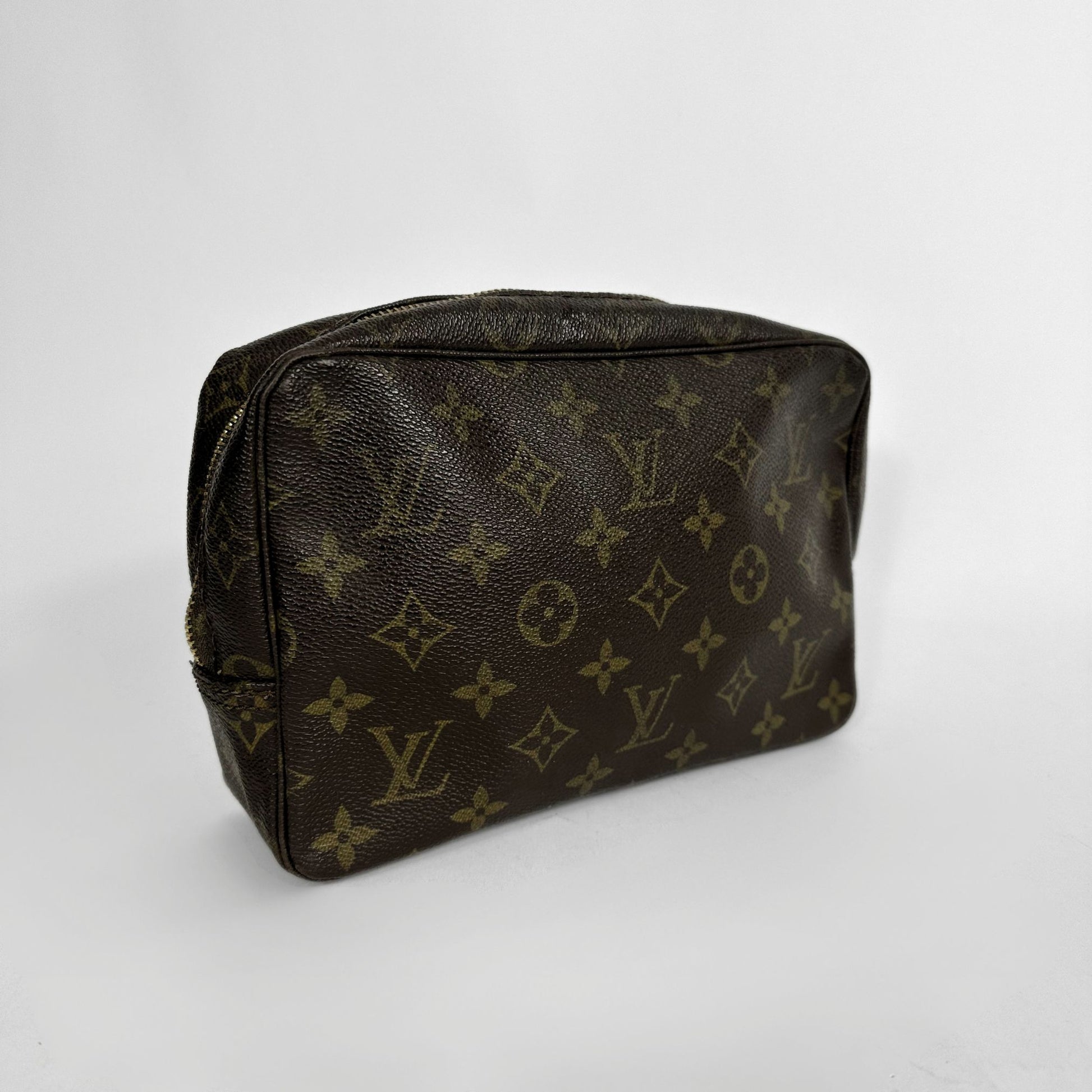 A Louis Vuitton monogram canvas cosmetic pouch in dark brown with tan monogram motifs, shown on a light gray background.