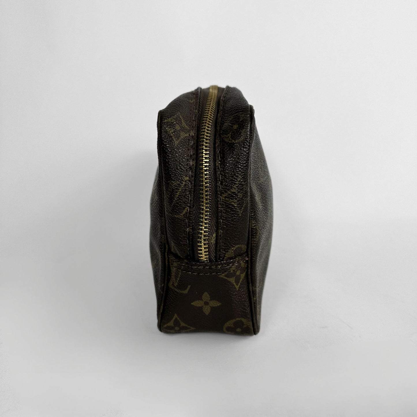 A Louis Vuitton monogram canvas pouch in dark brown with gold-toned hardware, photographed from the side against a light gray background.