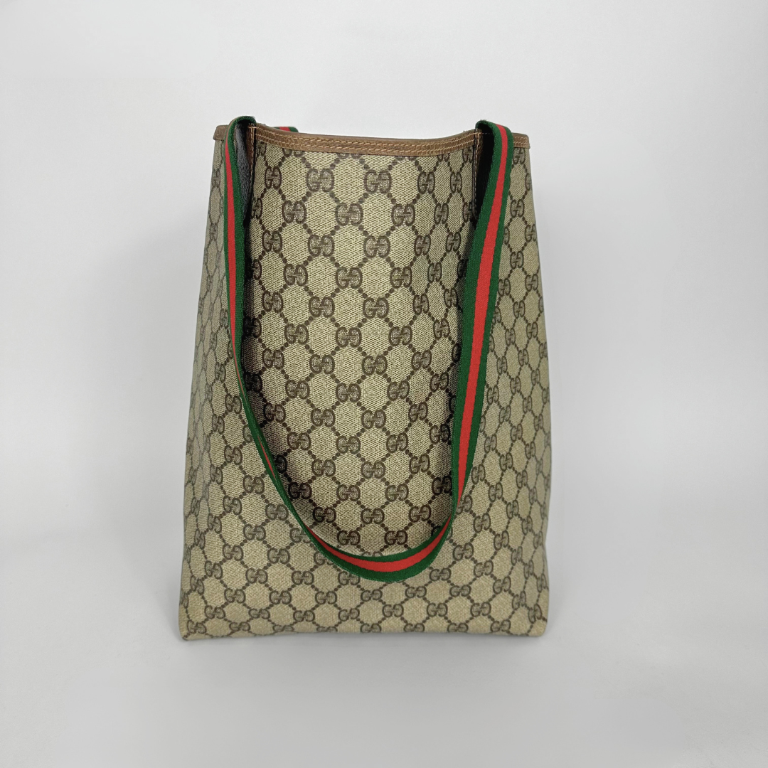 Designer tote bag with monogram pattern and red and green stripes on a light gray background