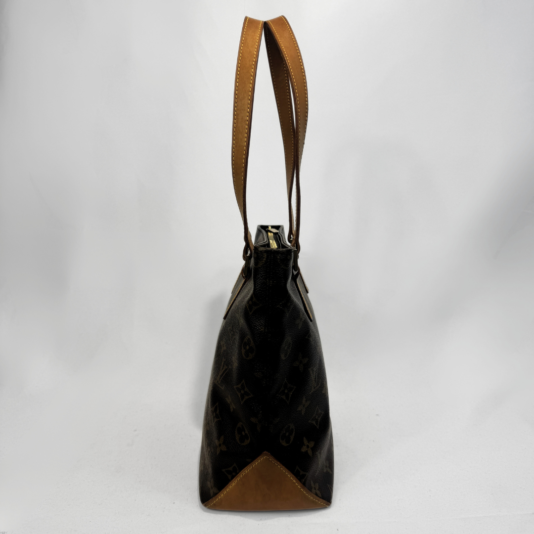 A Louis Vuitton monogram canvas shoulder bag in dark brown with tan leather trim and handles, shown from the side against a white studio background.
