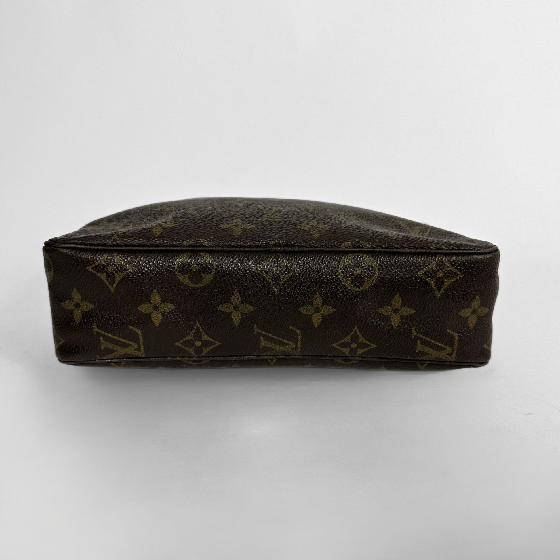 A Louis Vuitton monogram canvas pouch in dark brown with gold-tone monogram motifs, photographed from a top-down angle on a light gray background.