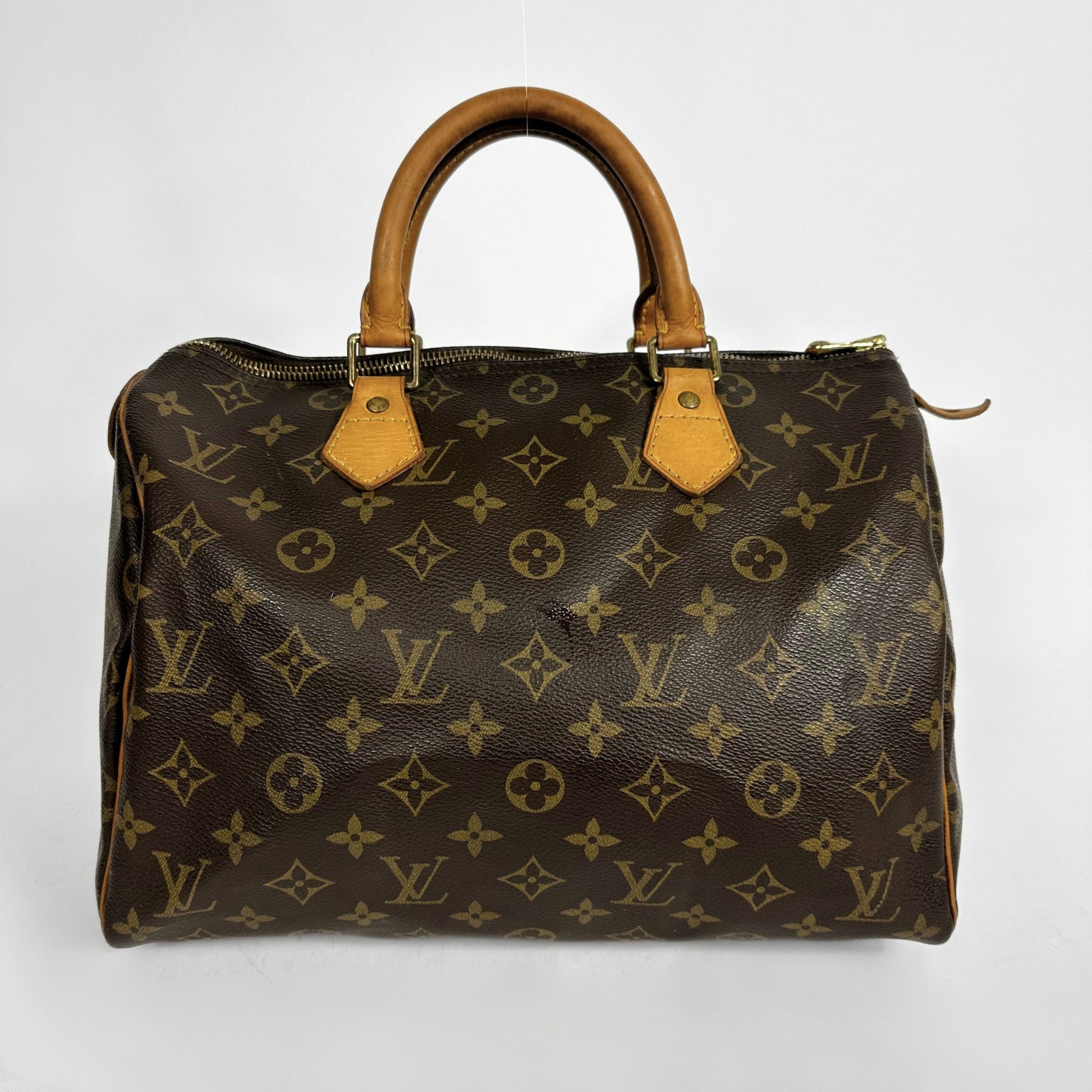 A Louis Vuitton monogram canvas Speedy handbag with tan leather handles and trim, photographed against a plain light gray background.