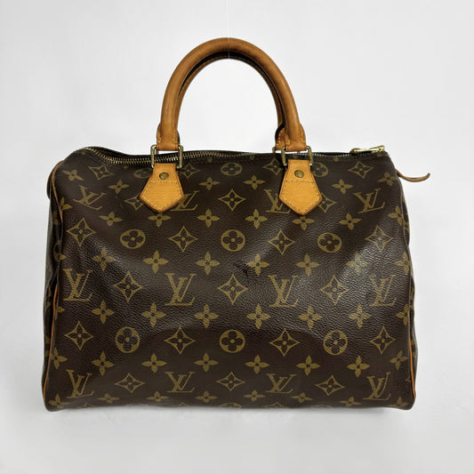 A Louis Vuitton monogram canvas Speedy handbag with tan leather handles and trim, photographed against a plain light gray background.