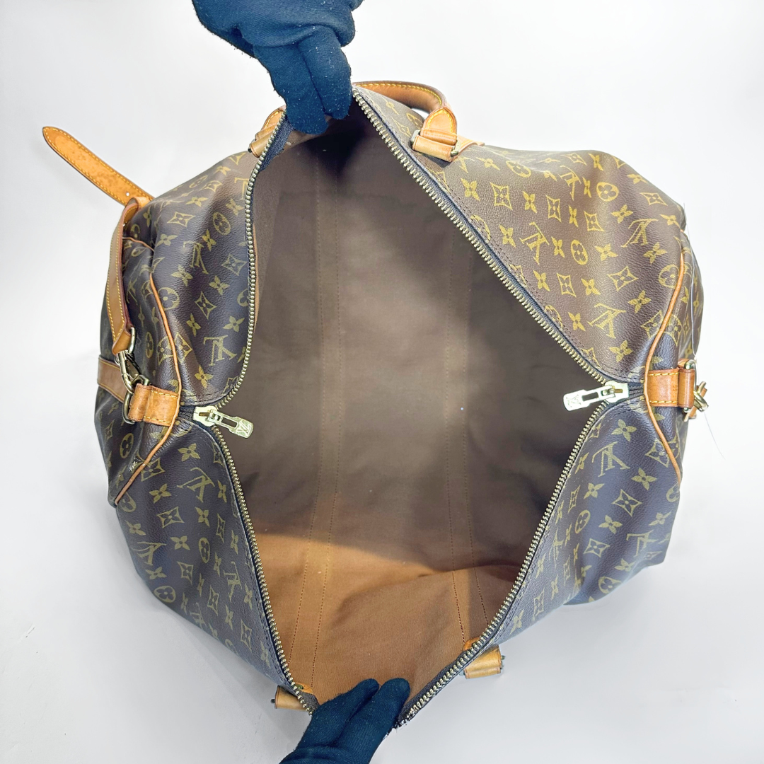 Louis Vuitton monogram bag with a hand opening it on a white background