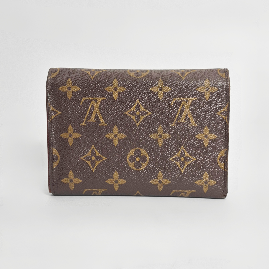 Brown wallet with gold monogram pattern on a light gray background