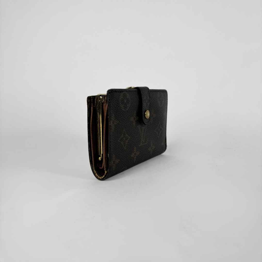 A Louis Vuitton monogram wallet in dark brown coated canvas with gold-tone hardware, shown standing upright on a light gray background.