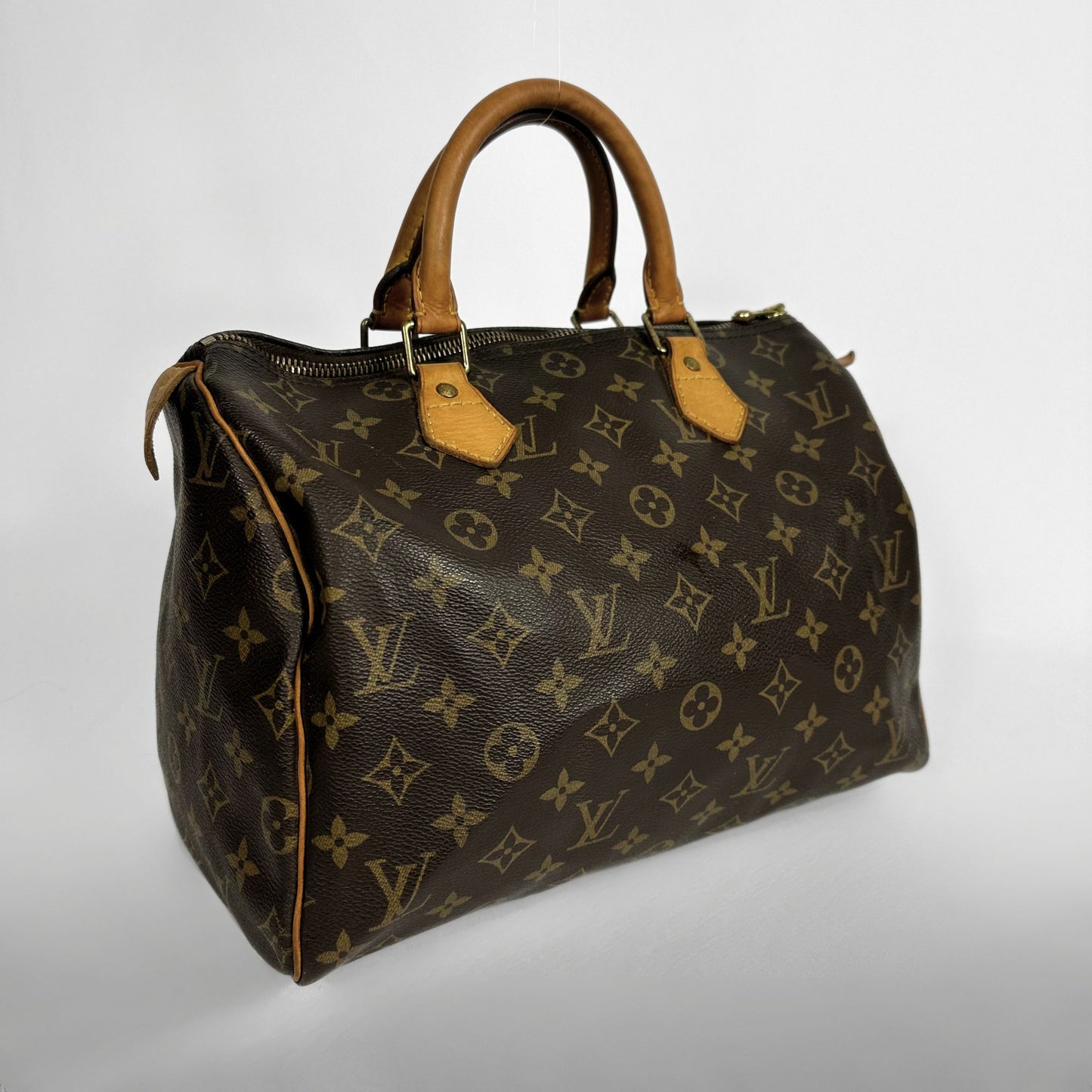 A Louis Vuitton monogram canvas Speedy handbag with brown leather handles and trim, shown on a light gray background.
