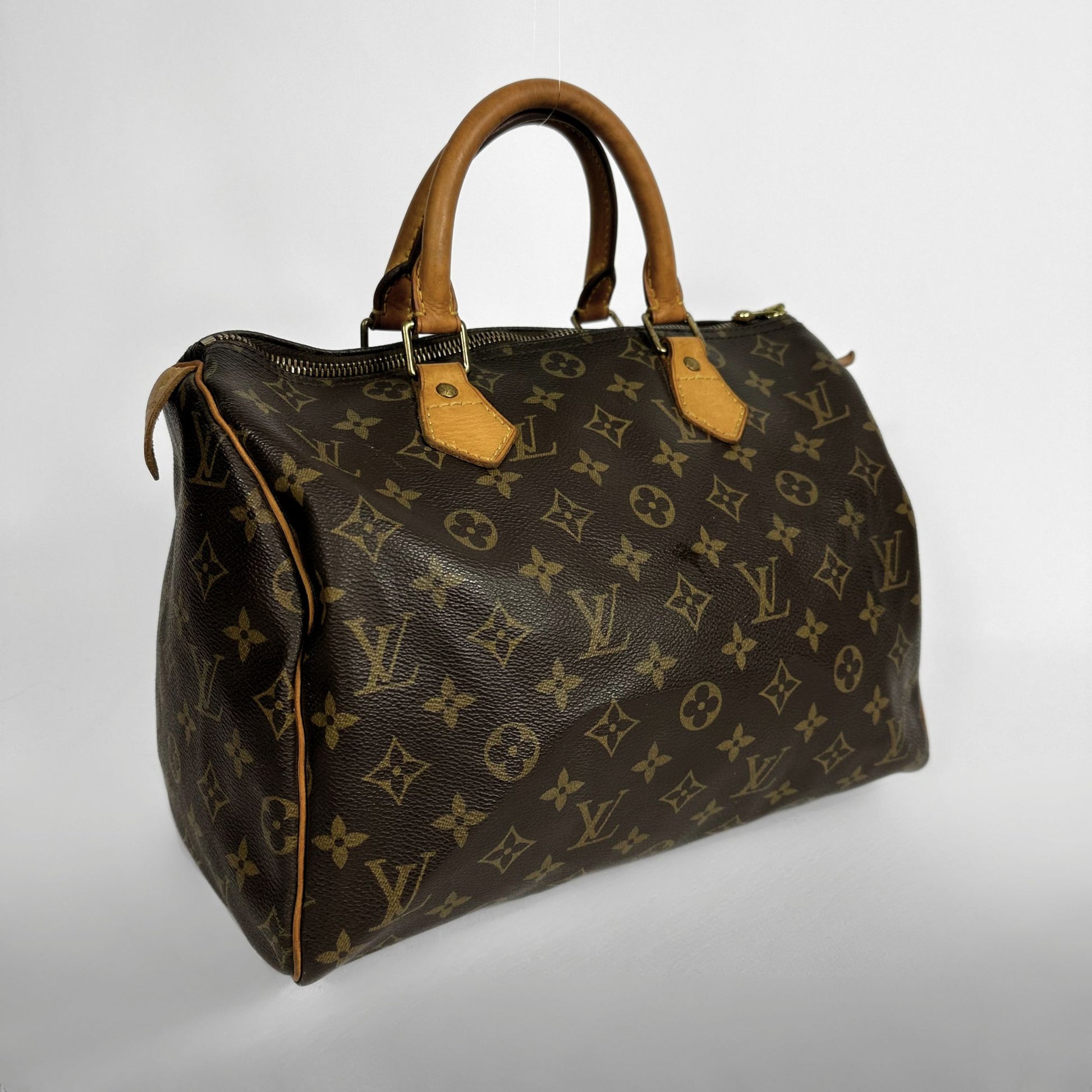 A Louis Vuitton monogram canvas Speedy handbag with brown leather handles and trim, shown on a light gray background.