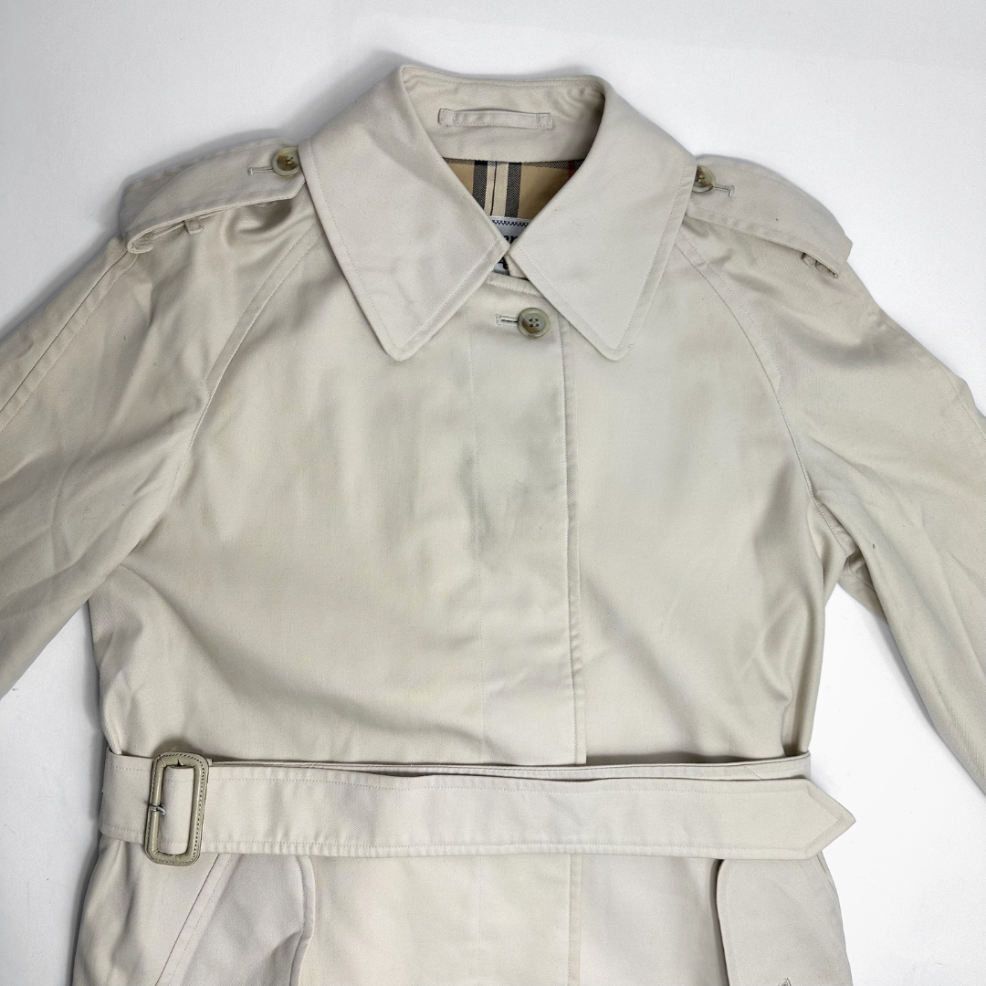 Beige trench coat on a mannequin against a gray background