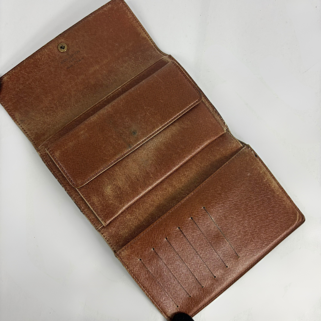 An open brown leather wallet with multiple card slots and pockets, photographed on a plain white background.