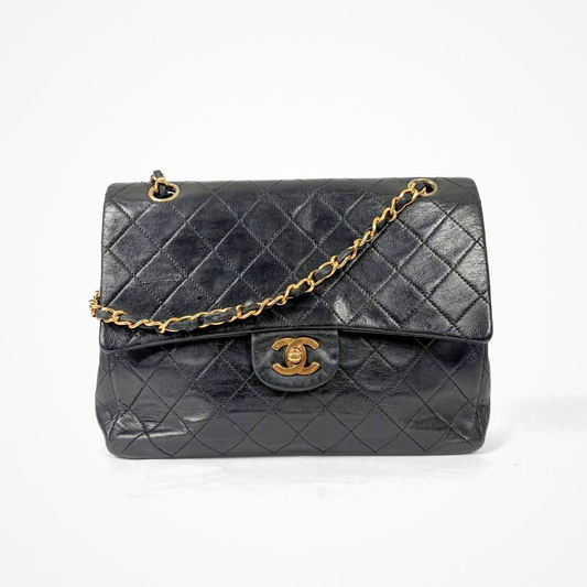 Black Chanel handbag with gold chain and clasp on a white background