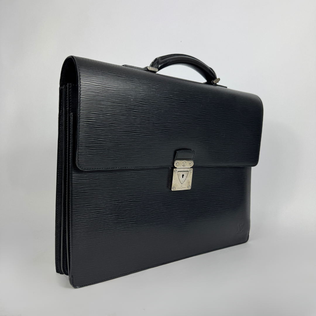 A black textured leather briefcase with a top handle and a silver-toned metal clasp, photographed on a light gray background.