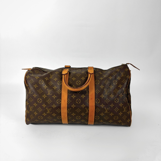 Brown patterned travel bag with tan handles on a white background