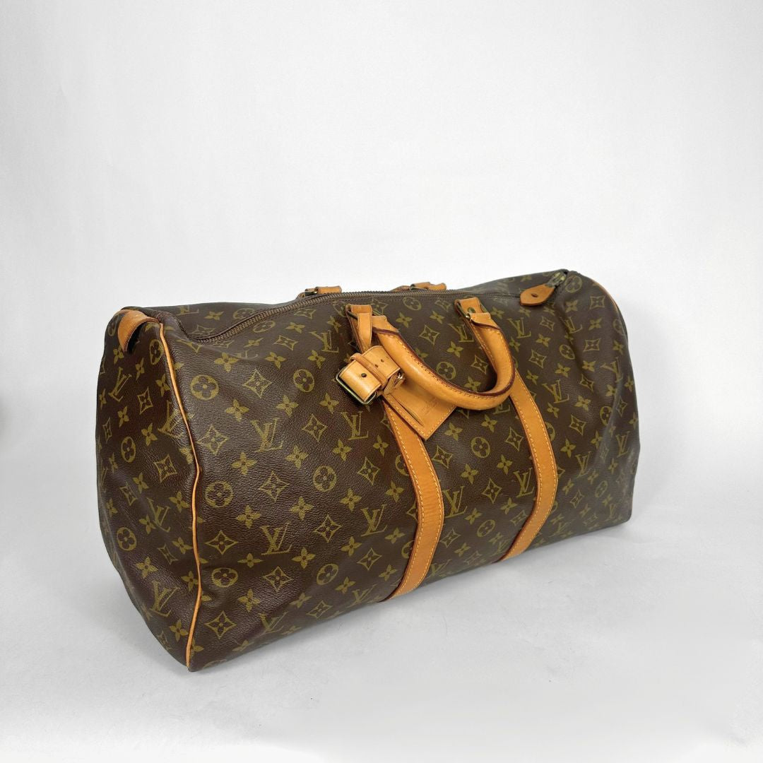 Brown monogram duffel bag with tan leather handles on a white background