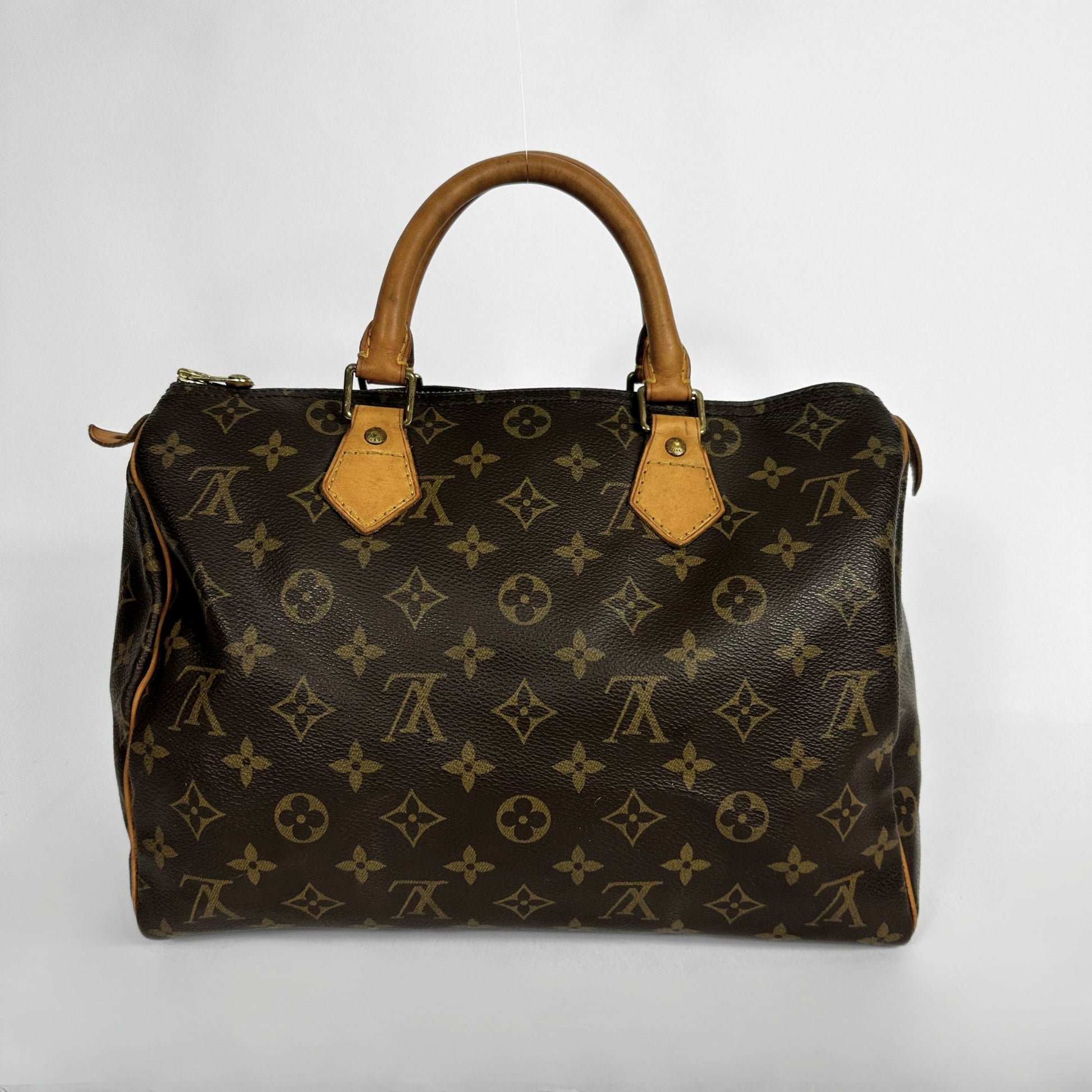 A Louis Vuitton monogram canvas Speedy bag with tan leather handles and trim, photographed against a plain light gray background.