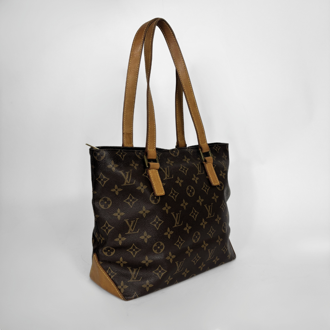 A Louis Vuitton monogram canvas tote bag with tan leather shoulder straps and trim, shown from a three-quarter angle against a light gray background.