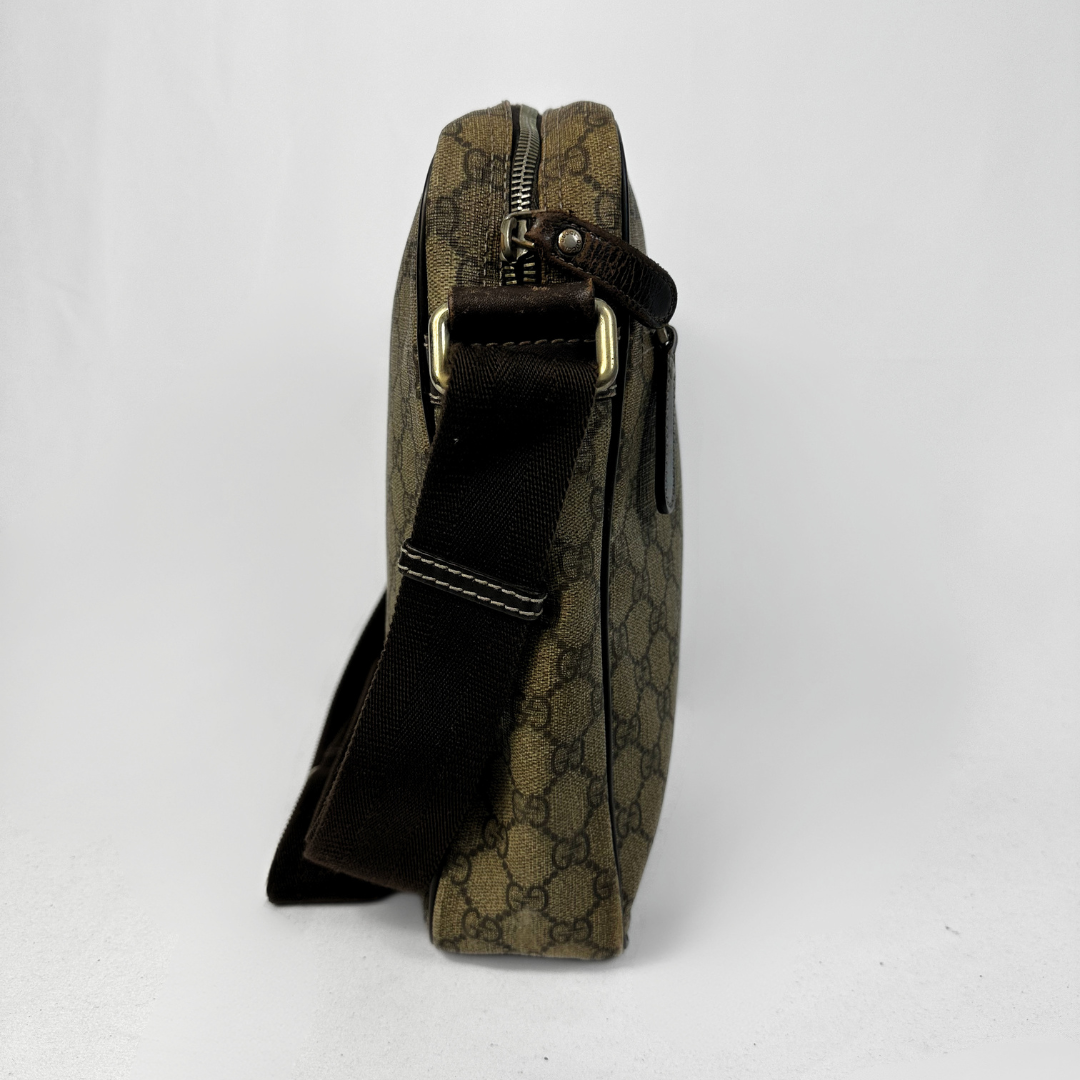 A vintage Gucci crossbody bag in brown GG Supreme canvas with a black leather strap and gold-tone hardware, shown from a side profile view against a white background.