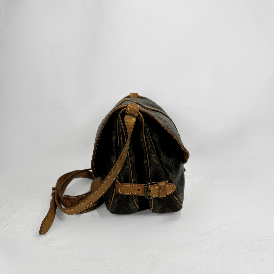 A Louis Vuitton monogram canvas shoulder bag in dark brown with tan leather trim and strap, shown from a side angle on a light gray background.