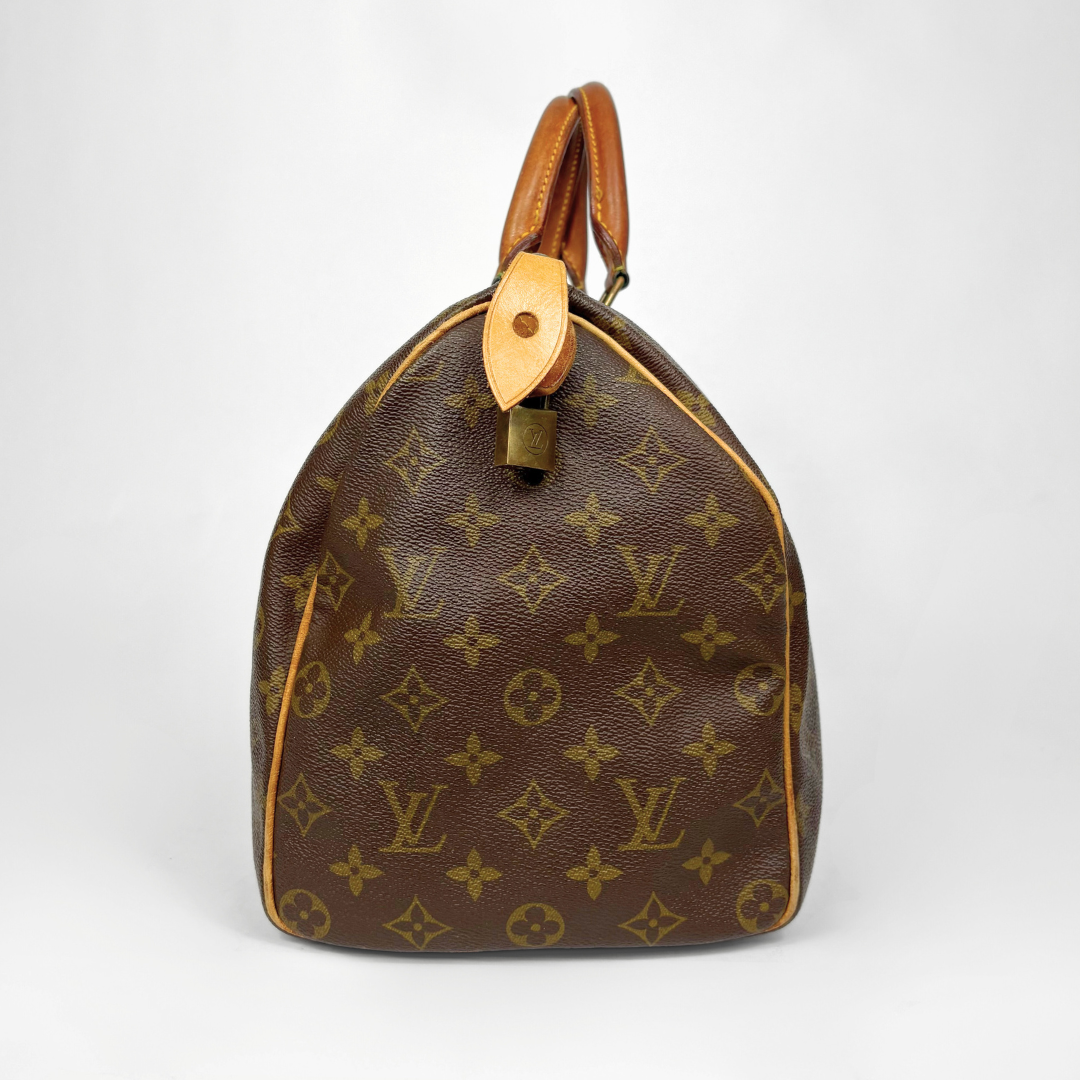 Brown leather handbag with monogram pattern on a white background