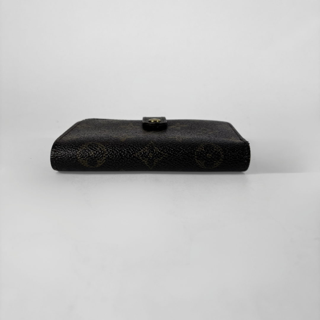 A black textured leather clutch wallet with a small gold-tone button clasp, displayed horizontally on a light gray background.