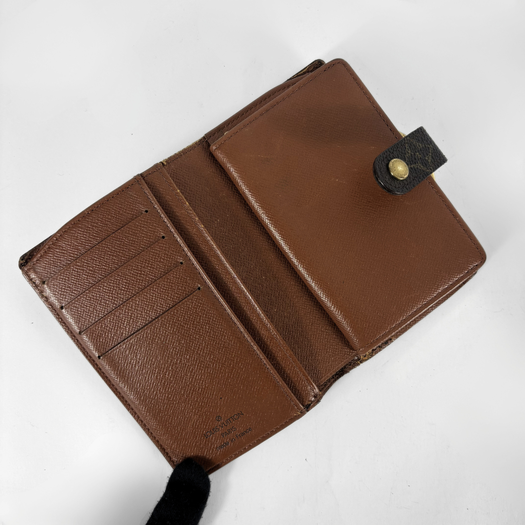 A brown textured leather bi-fold wallet shown open, displaying its interior card slots, a front slip pocket, and a black leather snap tab with a gold-tone button on a plain white background.