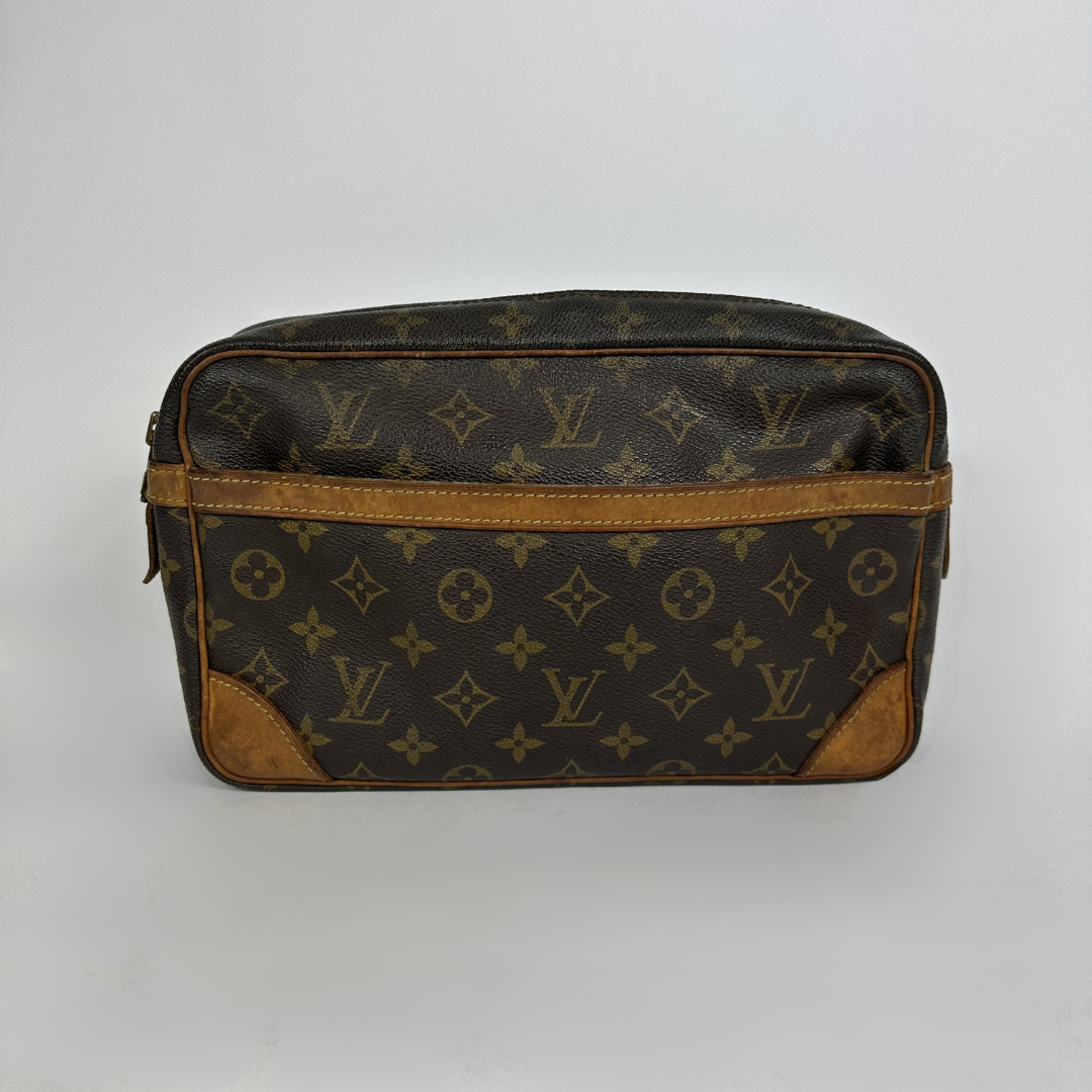 A Louis Vuitton monogram toiletry bag in brown coated canvas with tan leather trim and corner patches, shown against a plain light gray background.