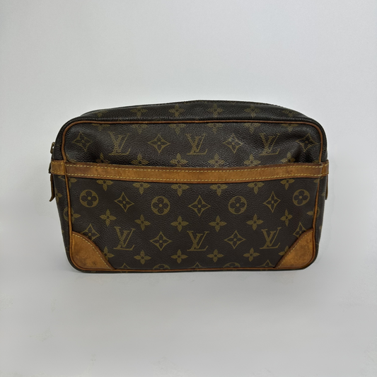 A Louis Vuitton monogram toiletry bag in brown coated canvas with tan leather trim and corner patches, shown against a plain light gray background.