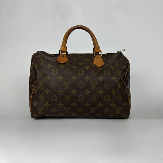 A Louis Vuitton monogram Speedy bag in dark brown coated canvas with tan leather handles and trim, photographed against a neutral light gray background.