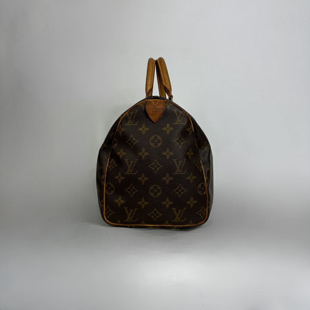 A Louis Vuitton monogram canvas duffel bag with brown leather handles and trim, photographed against a neutral light gray studio background.