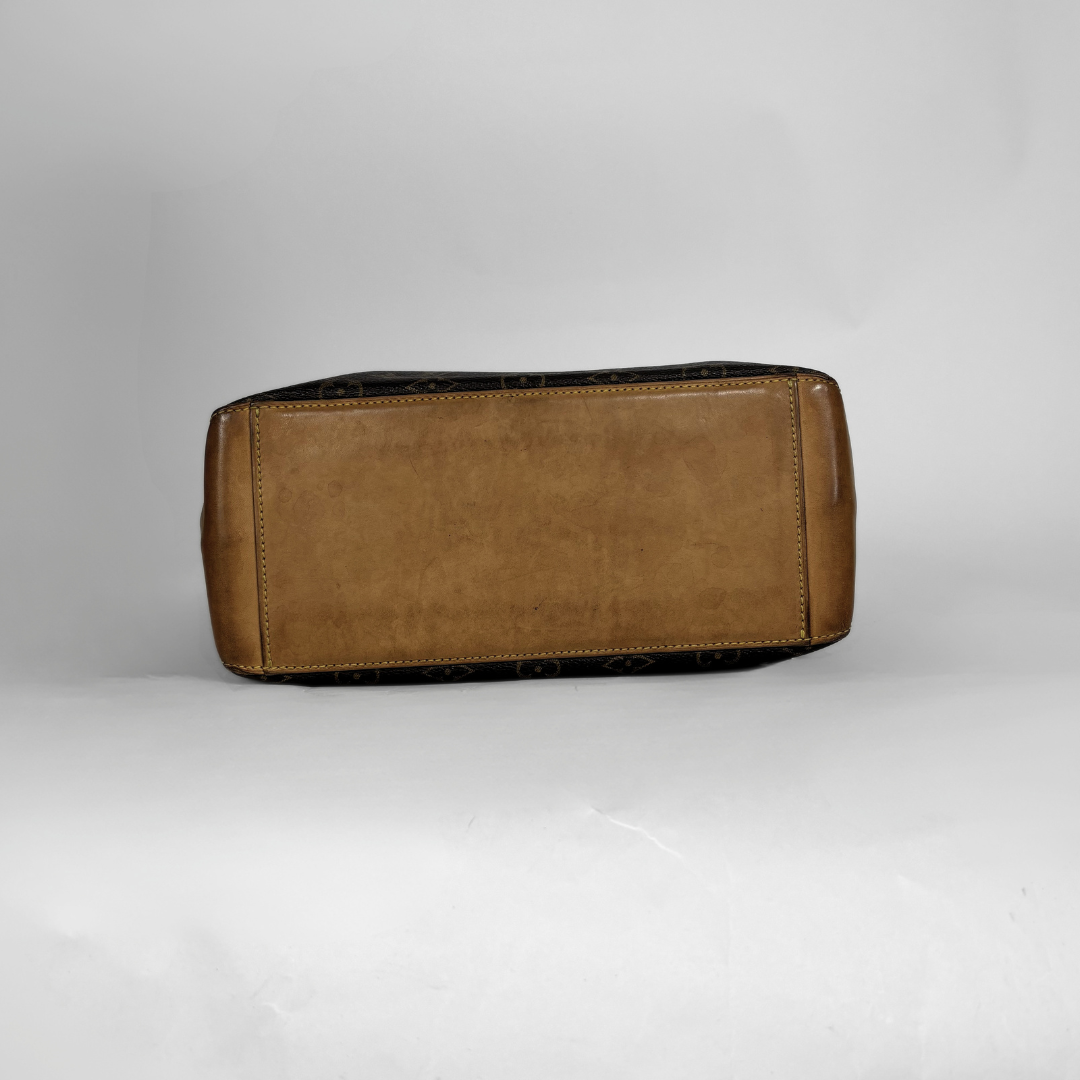 A Louis Vuitton monogram handbag shown from the bottom, featuring a tan leather base with dark brown monogram patterned sides, photographed on a light gray studio background.