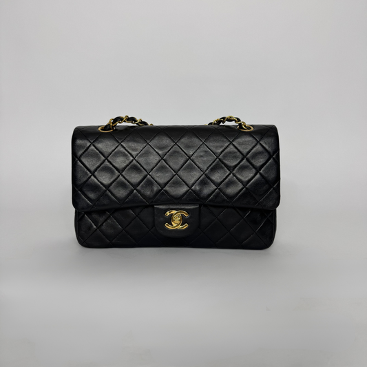 Black quilted handbag with gold hardware on a light gray background