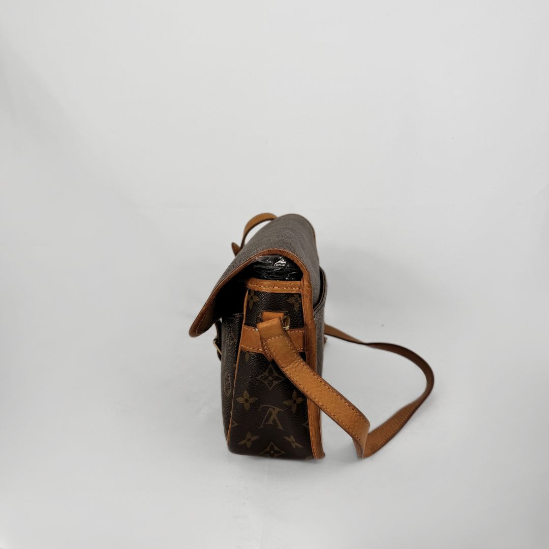 A Louis Vuitton monogram shoulder bag in brown coated canvas with tan leather trim and strap, shown from a side profile view on a light gray background.