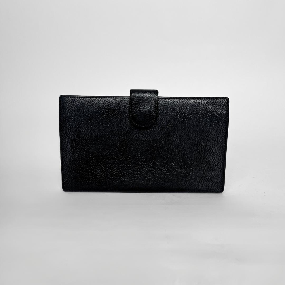 A black textured leather clutch wallet with a top strap closure, photographed against a neutral light gray background.