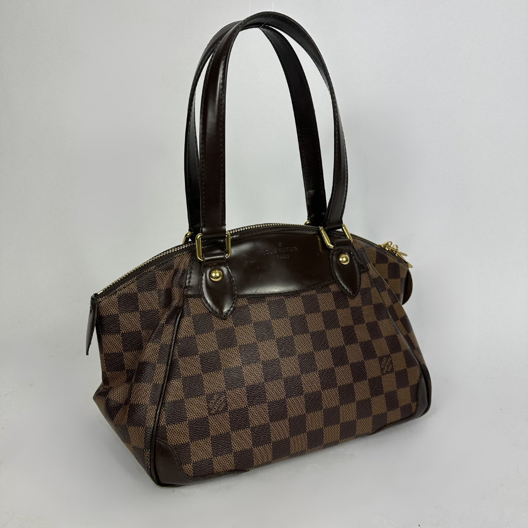 A Louis Vuitton handbag in the Damier Ebene in front of white background