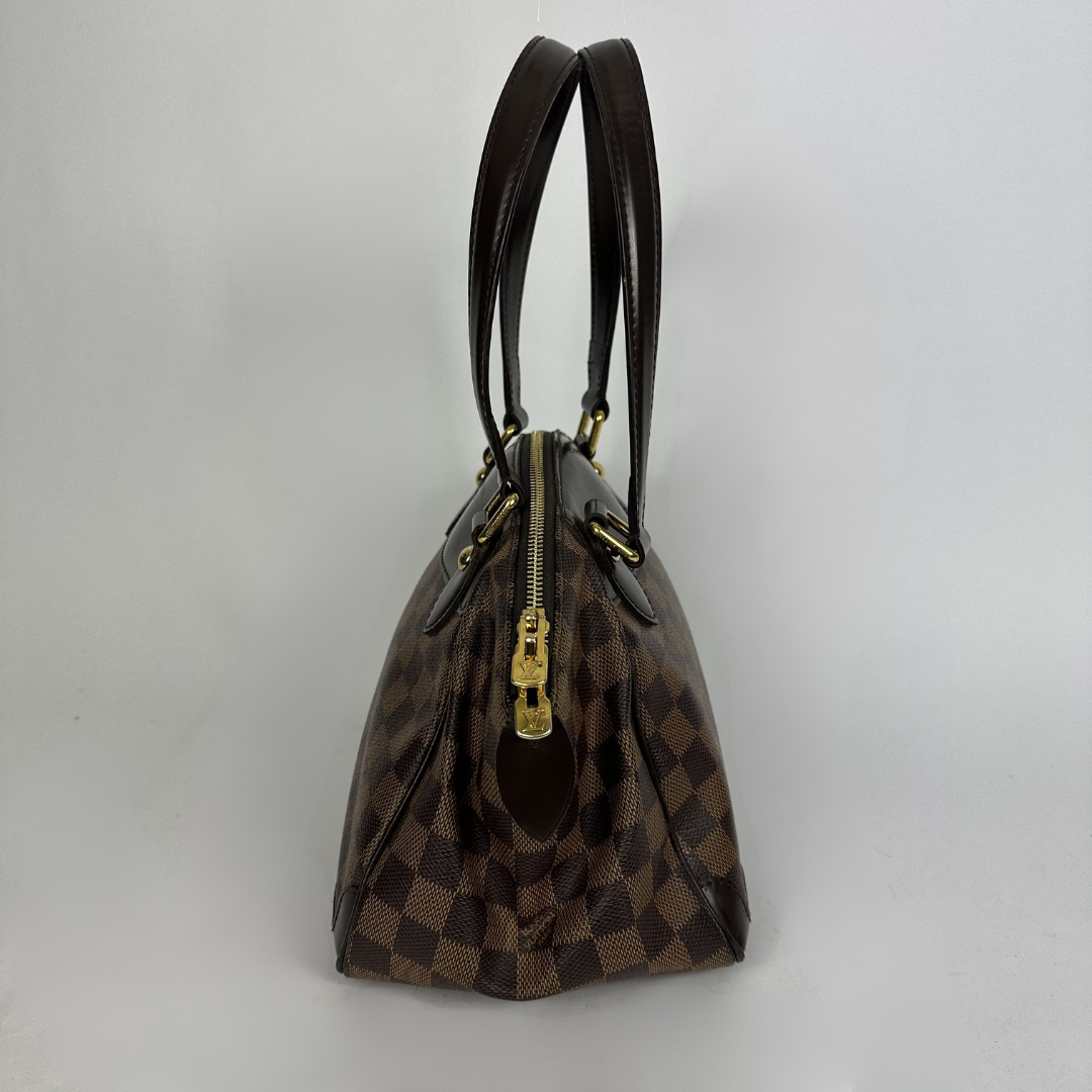 A Louis Vuitton handbag in the Damier Ebene in front of white background