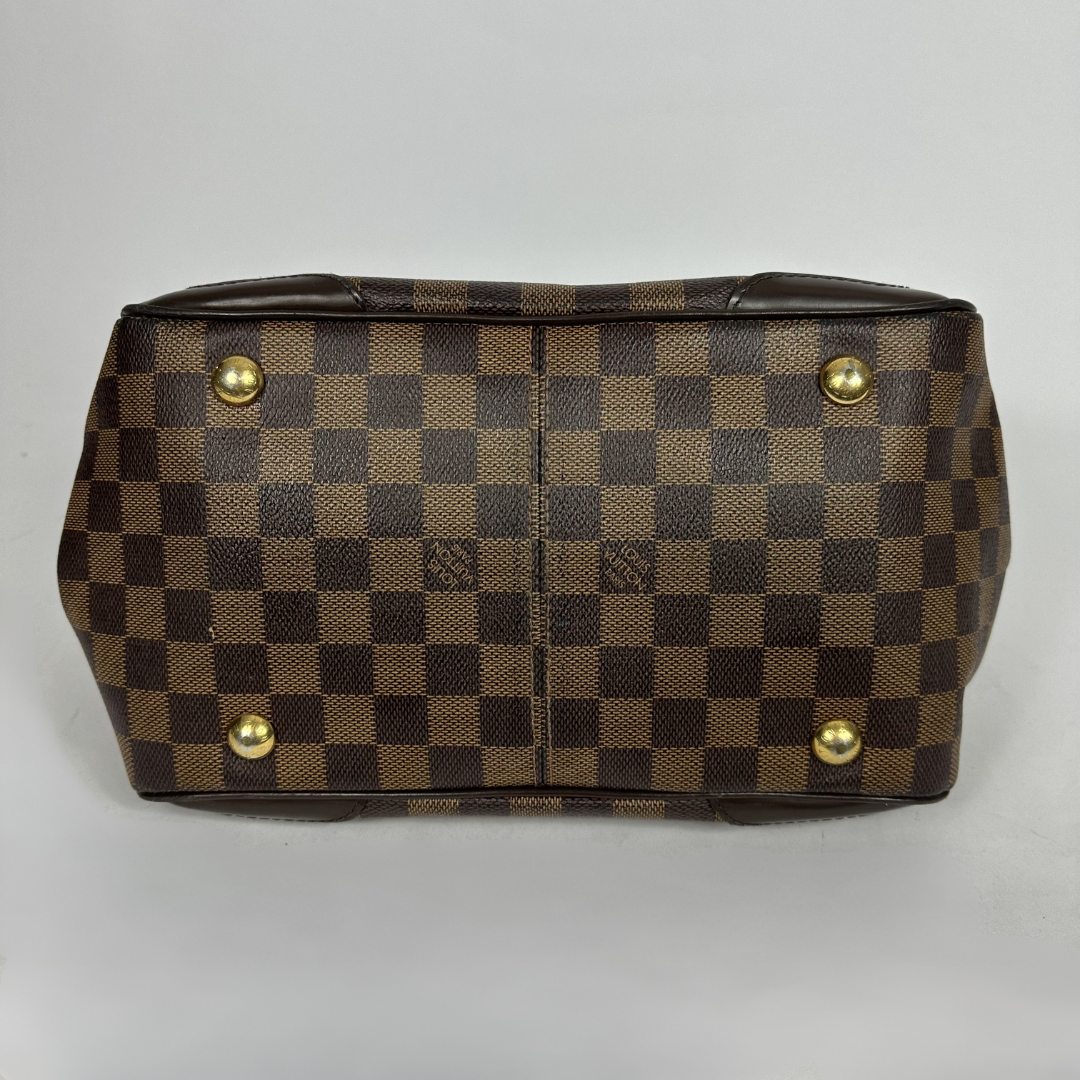 A Louis Vuitton handbag in the Damier Ebene in front of white background
