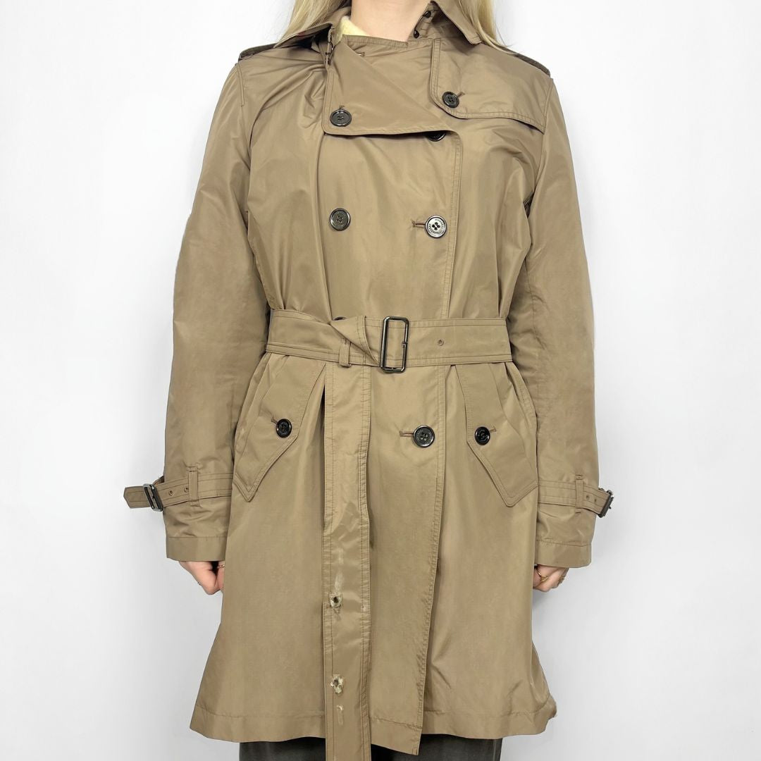 Beige trench coat worn by a person on a white background