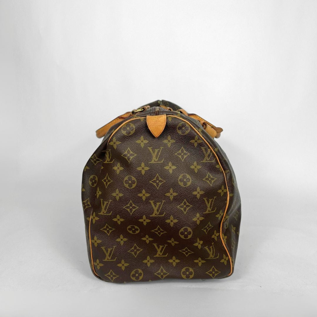 Brown monogram duffel bag with tan leather handles on a white background