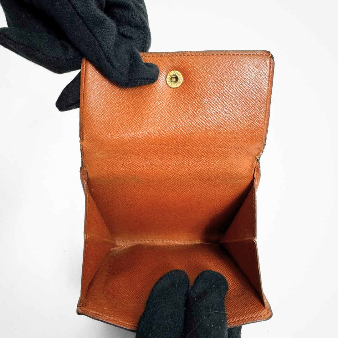 Brown leather wallet held by a gloved hand on a white background