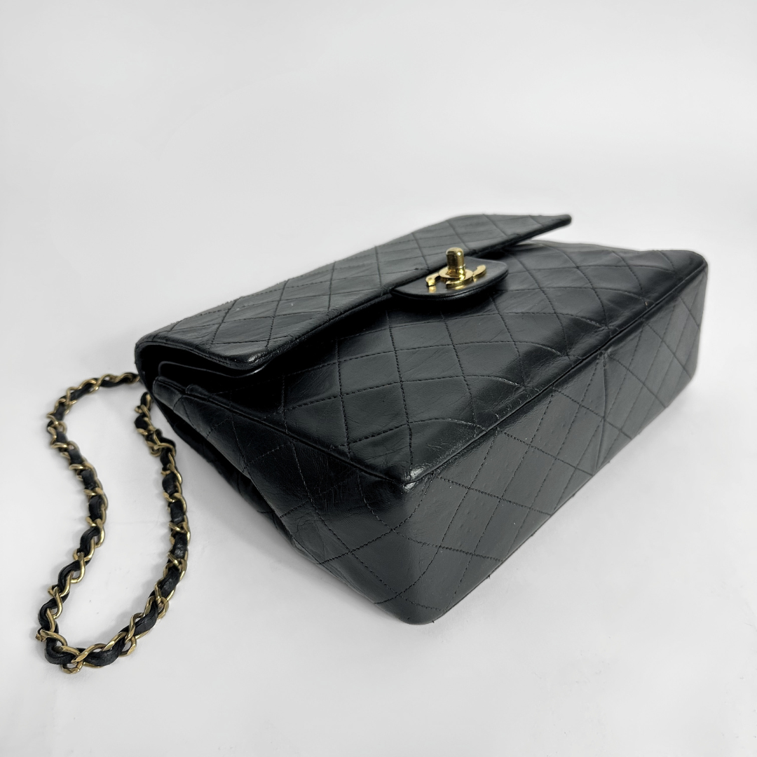 Black quilted handbag with a chain strap on a white background