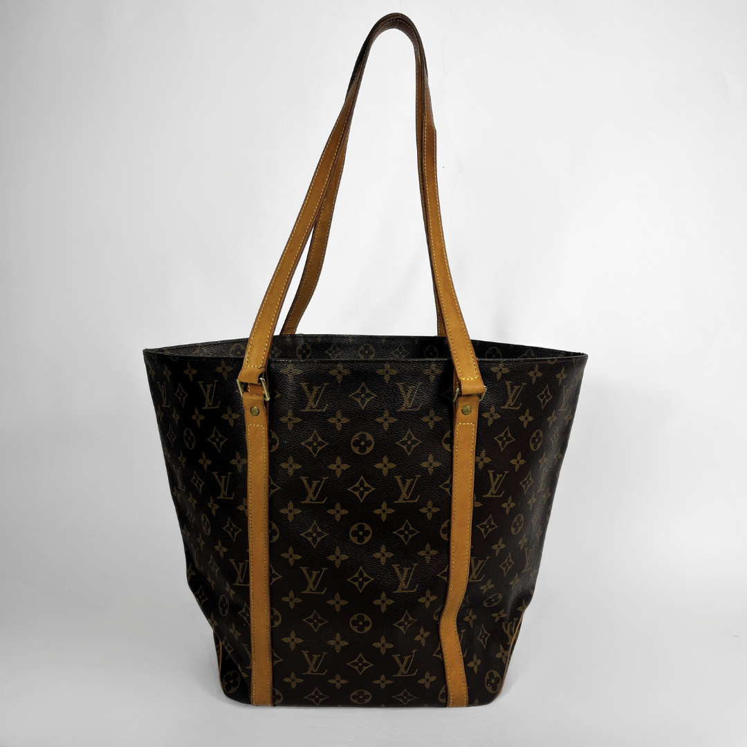 A Louis Vuitton monogram canvas tote bag with tan leather shoulder straps, shown against a neutral light gray background.
