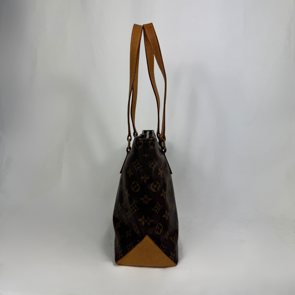 A Louis Vuitton monogram canvas tote bag with tan leather trim and shoulder straps, shown against a plain light gray background.