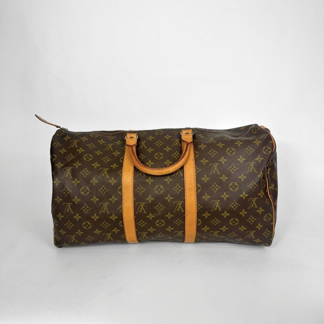 Brown monogram duffel bag with tan leather handles on a white background