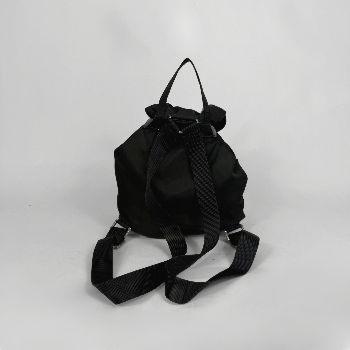 Black backpack and black ballet flats on a light gray background