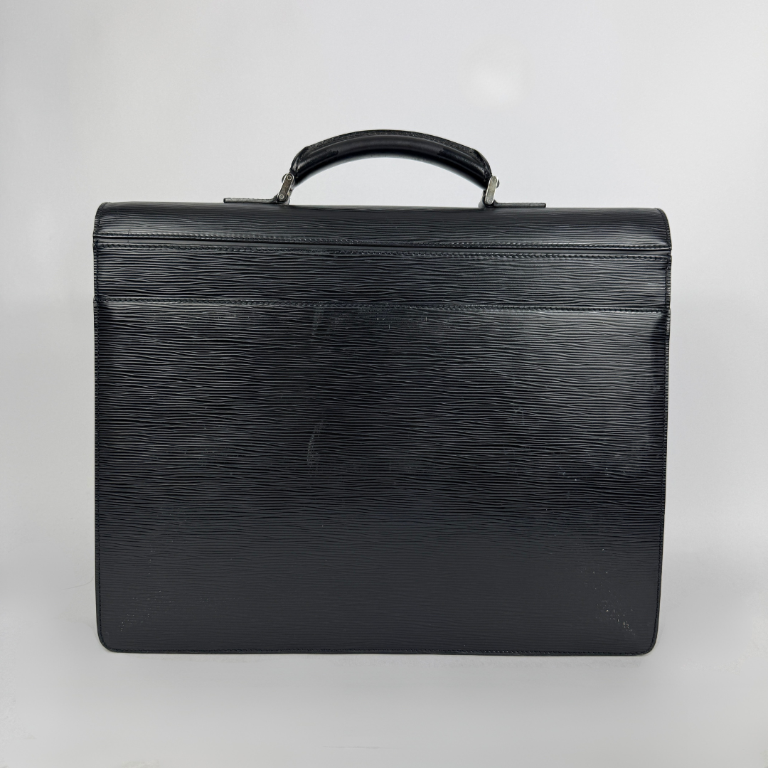 A black textured leather briefcase with a top handle, photographed against a neutral light gray background.