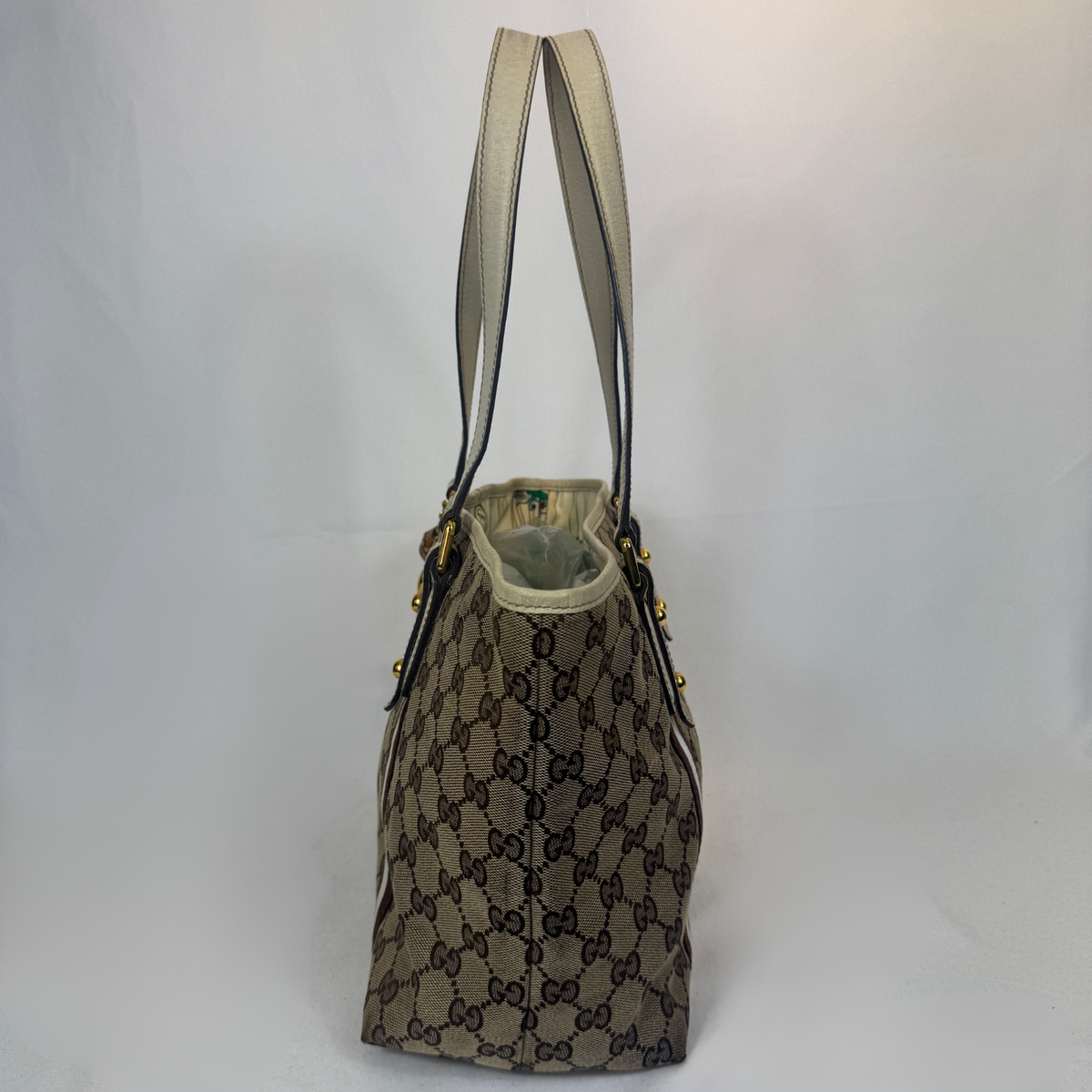 A Gucci tote bag in the classic GG Supreme canvas, featuring a beige and brown monogram pattern, dual shoulder straps, and gold-tone hardware, photographed against a plain white background.