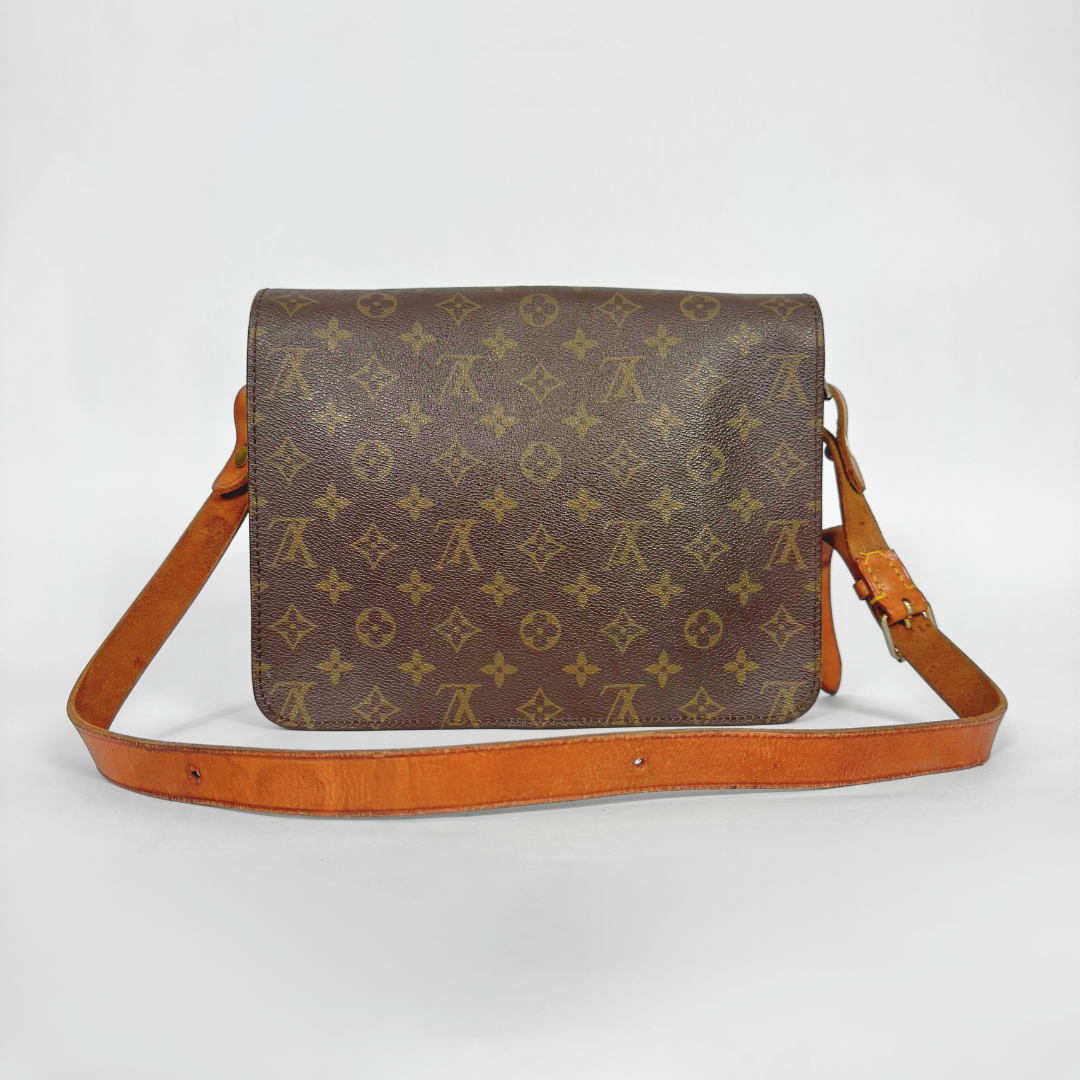 Brown monogram handbag with tan leather strap on a white background