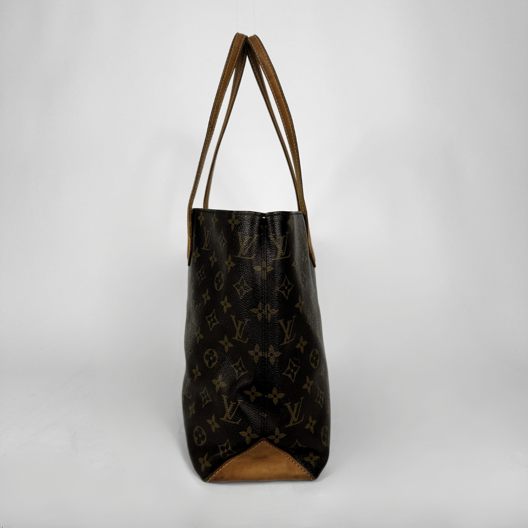 A Louis Vuitton monogram canvas tote bag with brown leather shoulder straps and a brown leather bottom trim, shown against a plain light gray background.